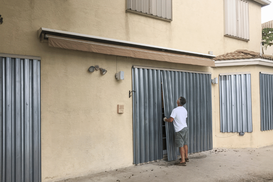Person installing storm shutters in preparation for a hurricane