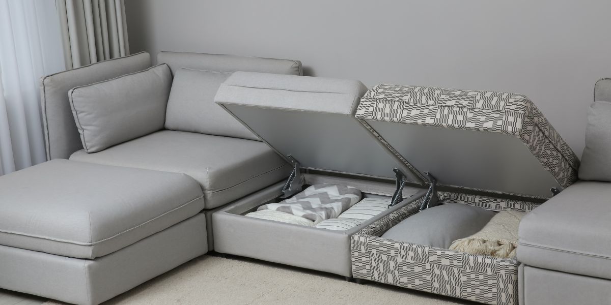 Grey modular sofa with an open ottoman storage compartment showing neatly folded blankets.