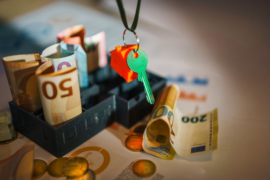 A minimalist and bright photo of house keys lying next to a piggy bank, symbolizing the financial savings involved in choosing a realtor.